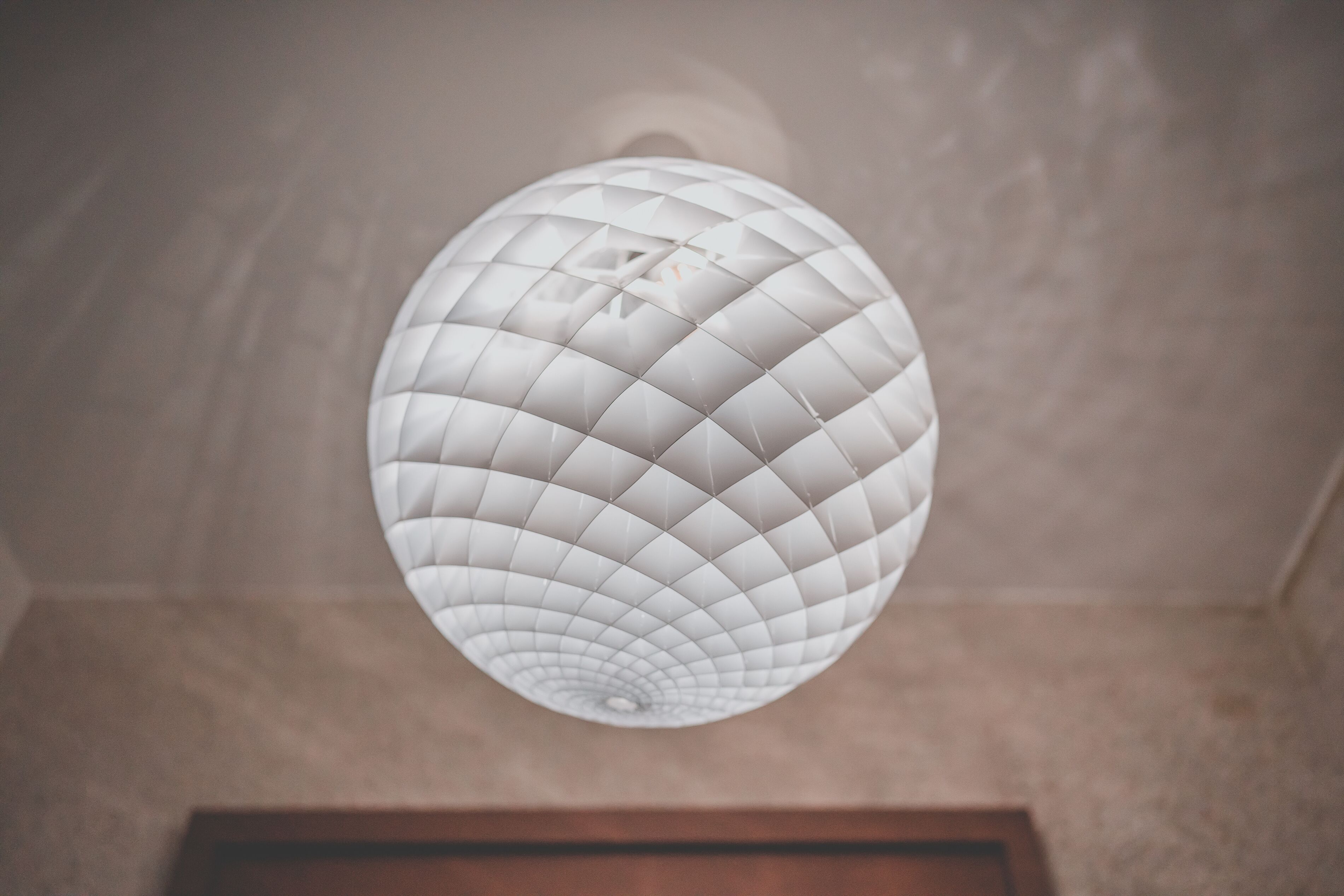 A ceiling with a geometric, white, spherical light fixture.