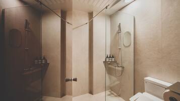 Un baño moderno con ducha de vidrio, inodoro y estante con artículos de aseo.