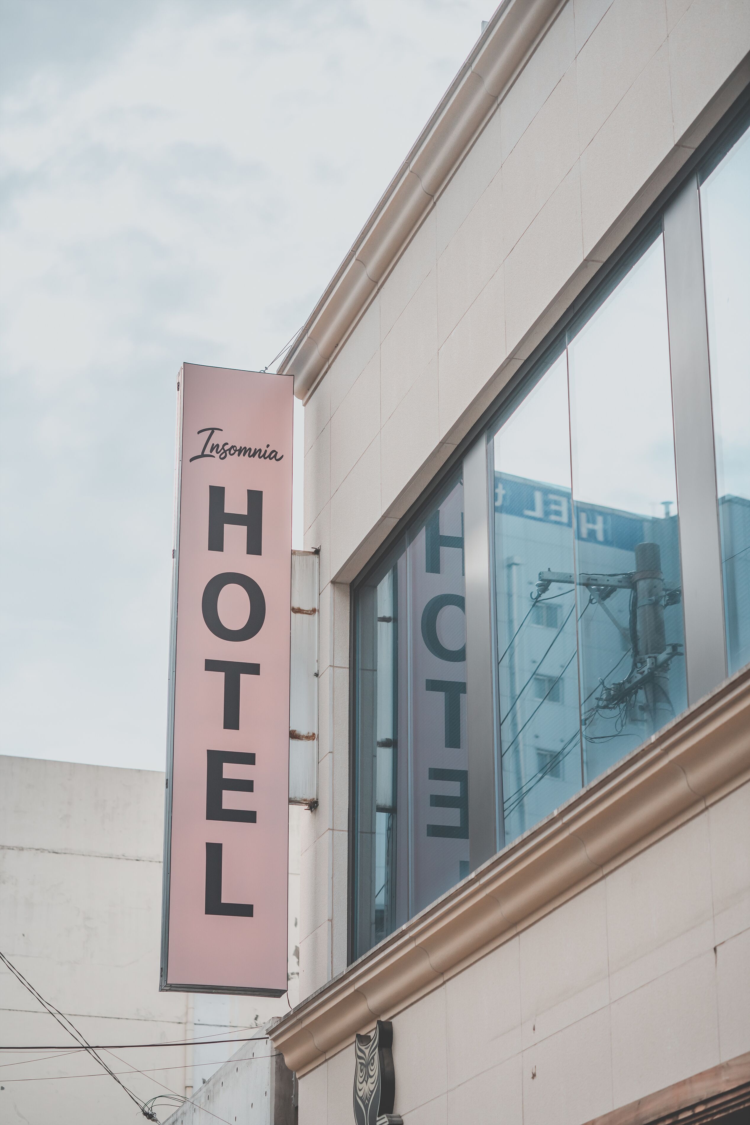 A hotel sign with the name 'Insomnia Hotel' on a pink background.