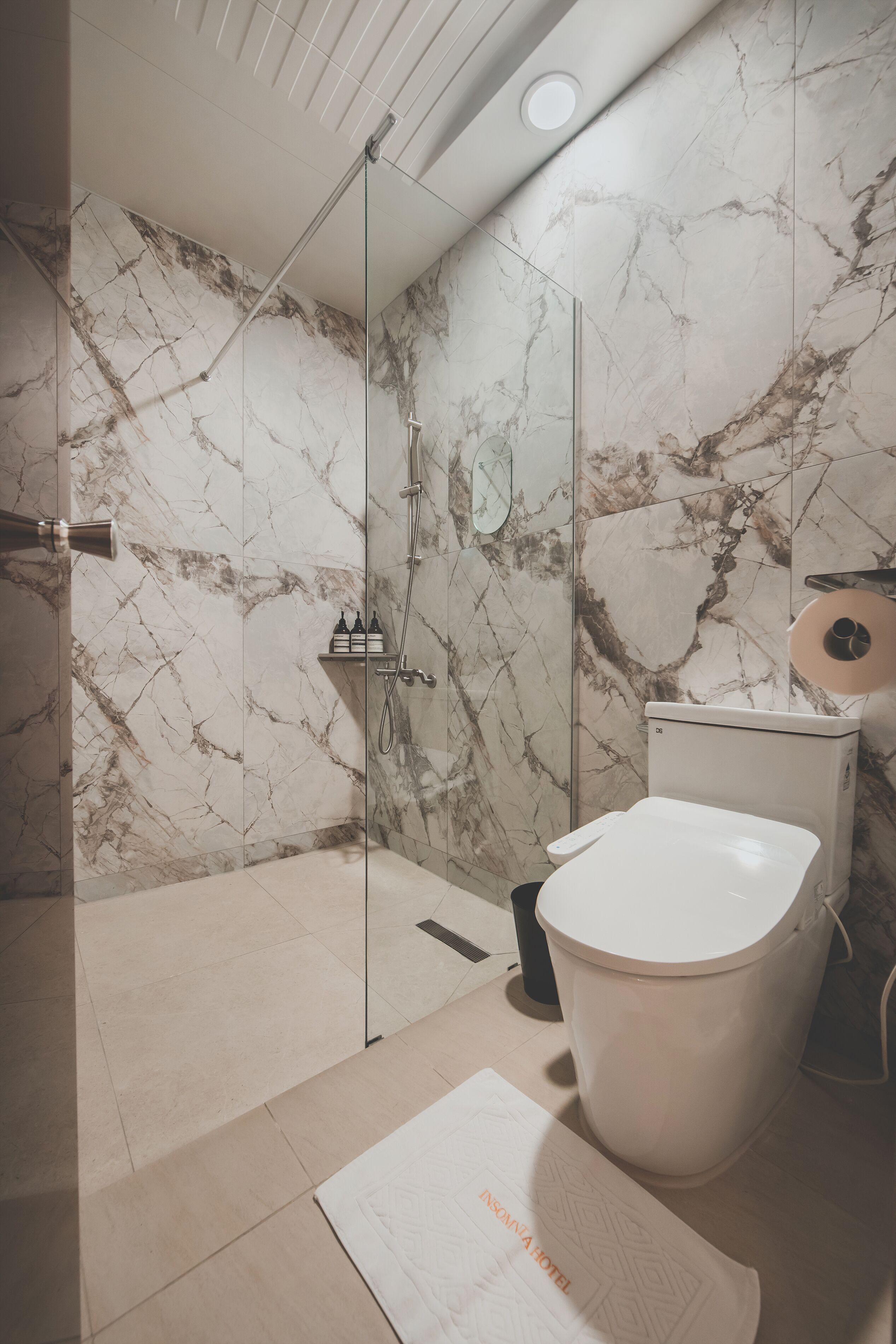 Ein Badezimmer mit einer gläsernen Duschkabine, einer Toilette und einem Waschbecken.