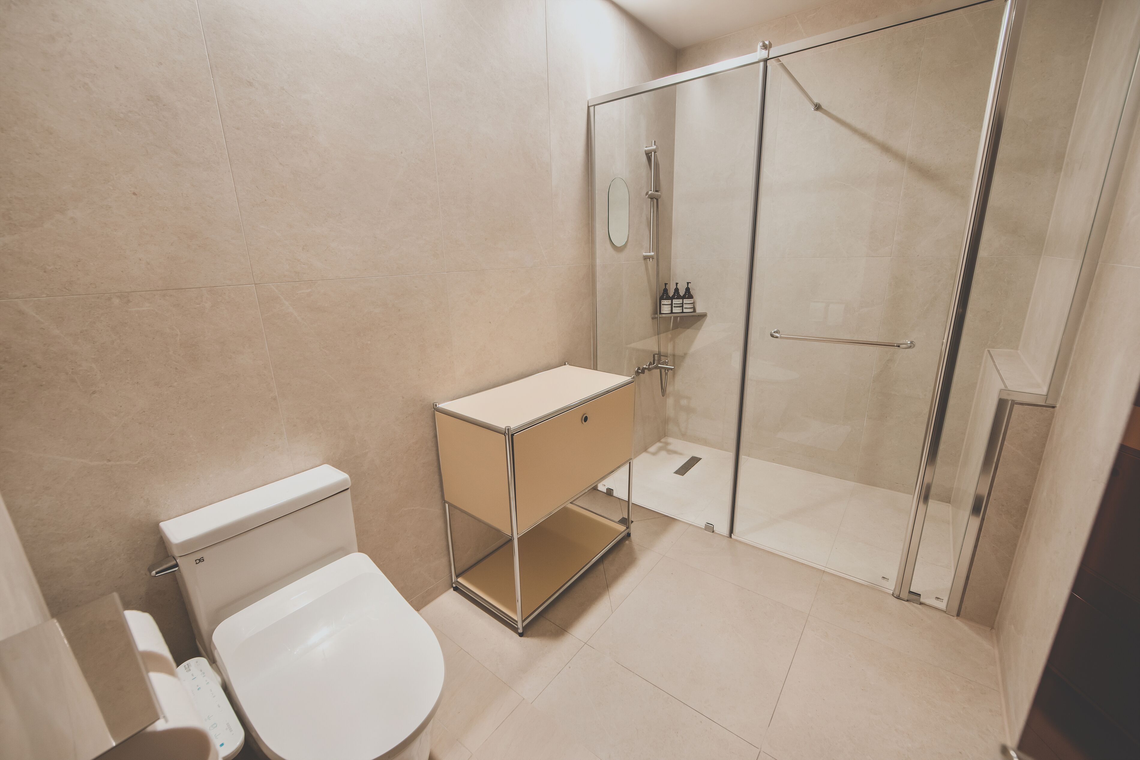 A modern bathroom with a toilet, a sink with a mirror, and a glass-enclosed shower.