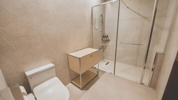 A modern bathroom with a toilet, a sink with a mirror, and a glass-enclosed shower.