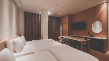 A hotel room with a bed, a desk, and a television.
