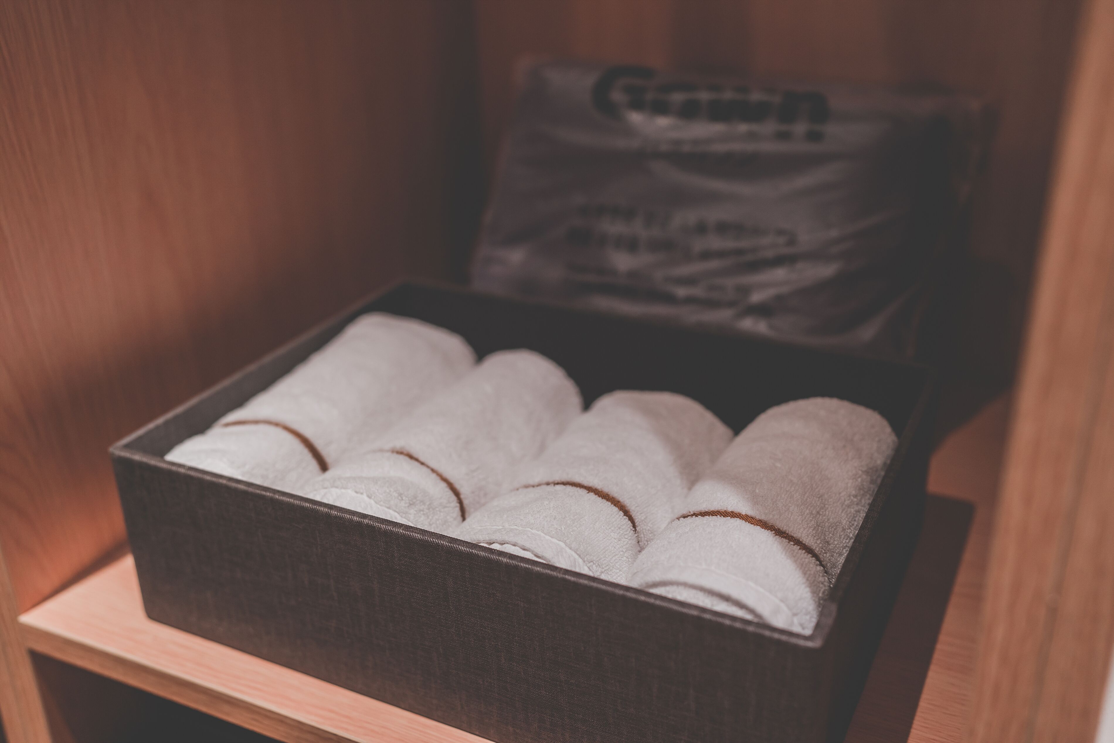 A box containing neatly rolled towels placed on a wooden surface.