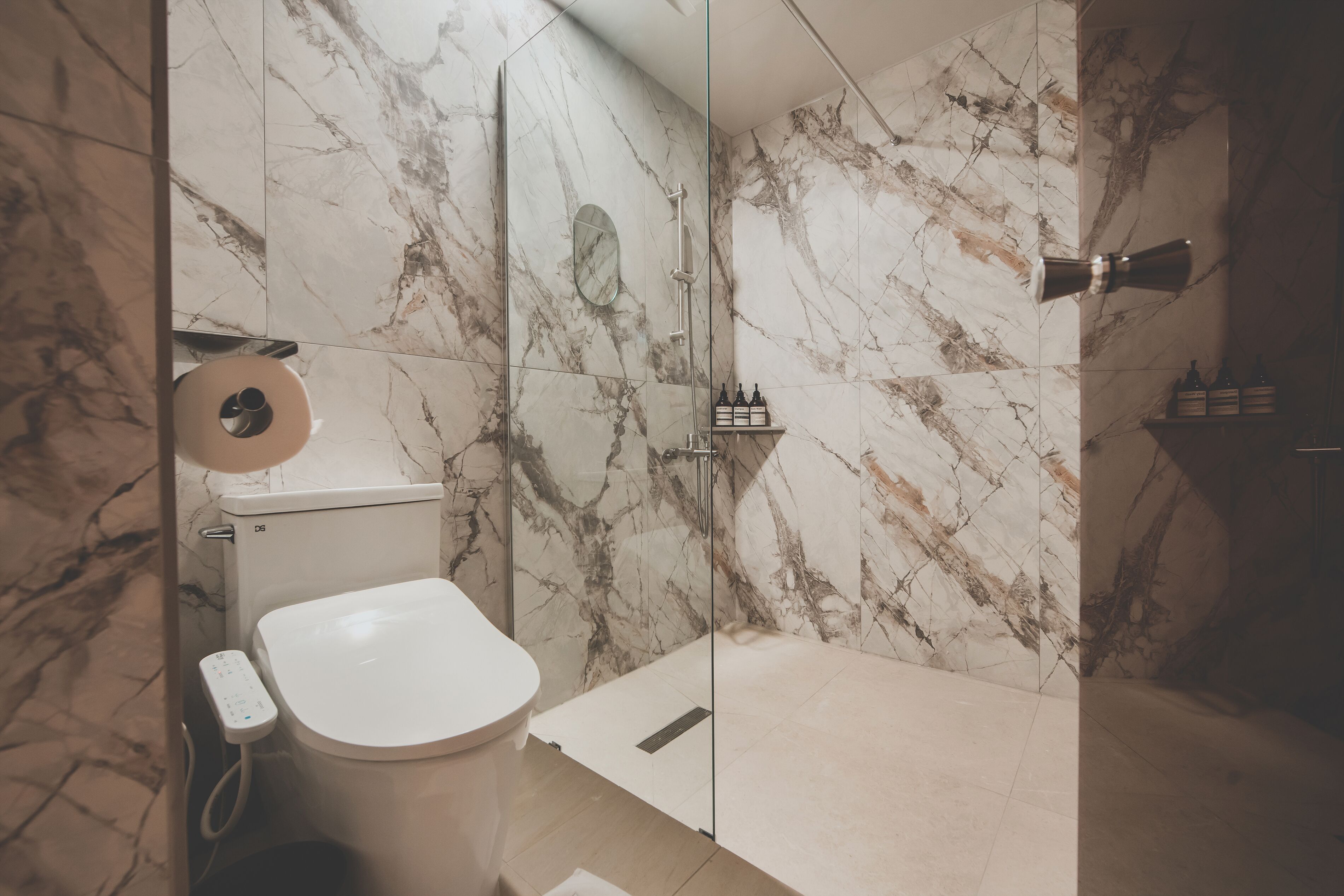 Un baño moderno con inodoro, ducha y paredes de mármol.