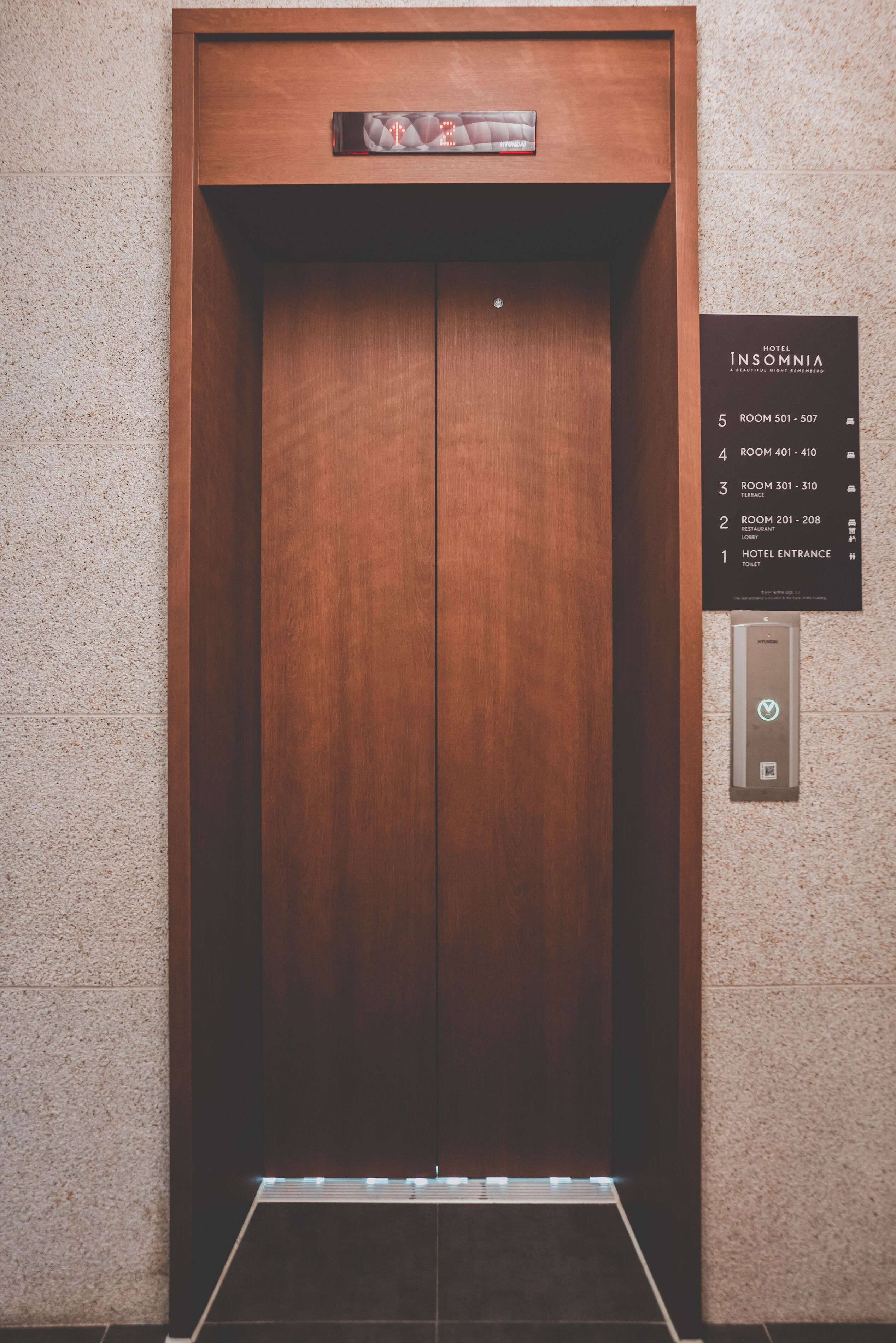 An elevator with a wooden finish and a digital display at the top.