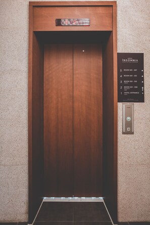 Ascensor con detalles de madera y una pantalla digital en la parte superior.