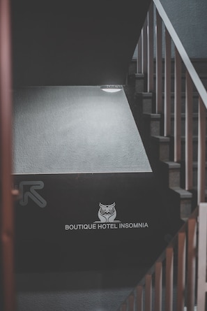 Una scala con un muro strutturato e il logo dell'hotel Boutique Insomnia.