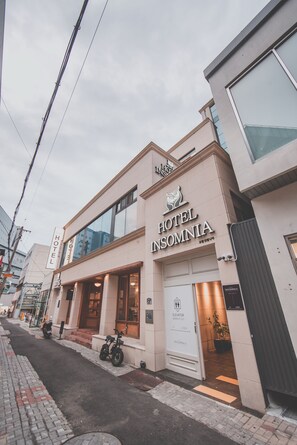 A hotel with a modern facade, signage for 'HOTEL INSOMNIA,' and a visible elevator sign. - Hotel Insomnia (Daegu)