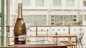 A bottle of champagne on a glass tray with a view of a building in the background.