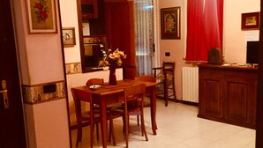 A dining area with a wooden table and chairs, a vase with flowers, and a kitchen in the background. - holiday home IL GIRASOLE (Castel Ritaldi)