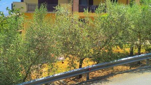 A yellow building with a tiled roof, surrounded by olive trees, and a metal guardrail in the foreground. - holiday home IL GIRASOLE (Castel Ritaldi)