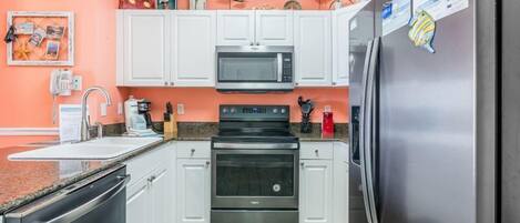 A kitchen with white cabinets, a stainless steel refrigerator, a microwave, and an oven.