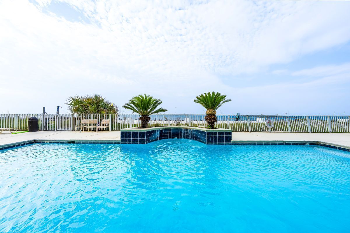 A swimming pool with a clear blue sky and a fence in the background.
