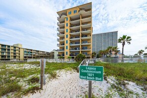 A multi-story building with balconies, a sign indicating 'Legacy Condominium 1821 West Beach Blvd.'