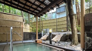 A hot spring area with a tiled pool, bamboo fences, and lounge chairs.