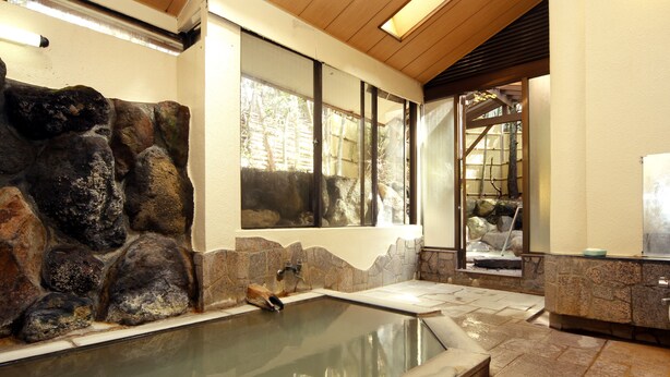 A spa area with a stone wall, a hot tub, and a wooden ceiling.