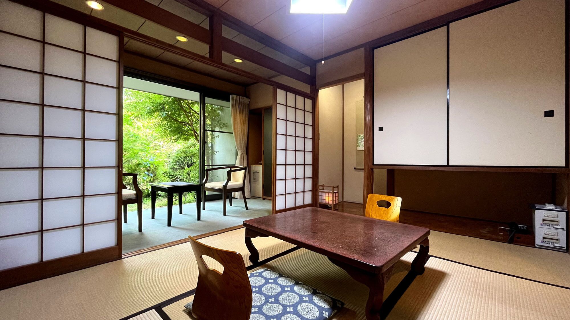 A traditional Japanese room with tatami flooring, a low table, and sliding doors.