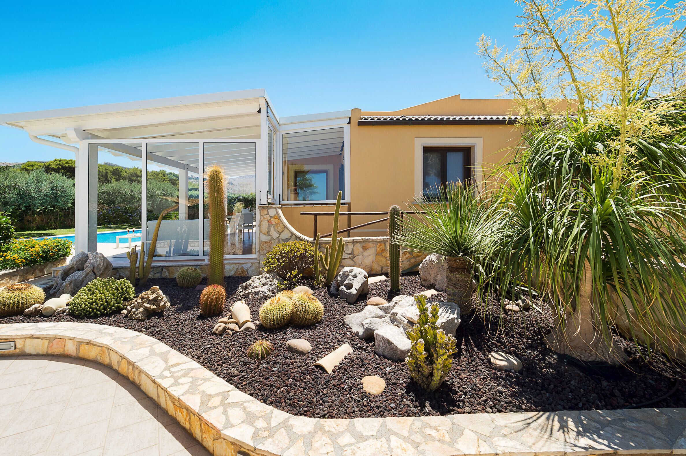 Ein modernes Haus mit Pool, umgeben von verschiedenen Kakteen und Sukkulenten.