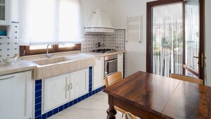 Una cocina con lavaplatos, estufa, horno y una mesa de comedor con sillas.