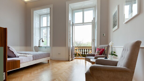 A bedroom with a bed, a chair, a desk, and a window.