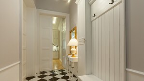 A hallway with a checkered floor, a white bench, and a mirror with a gold frame.