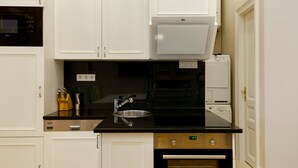 A kitchen with white cabinets, a black countertop, a stainless steel sink, and a built-in oven.