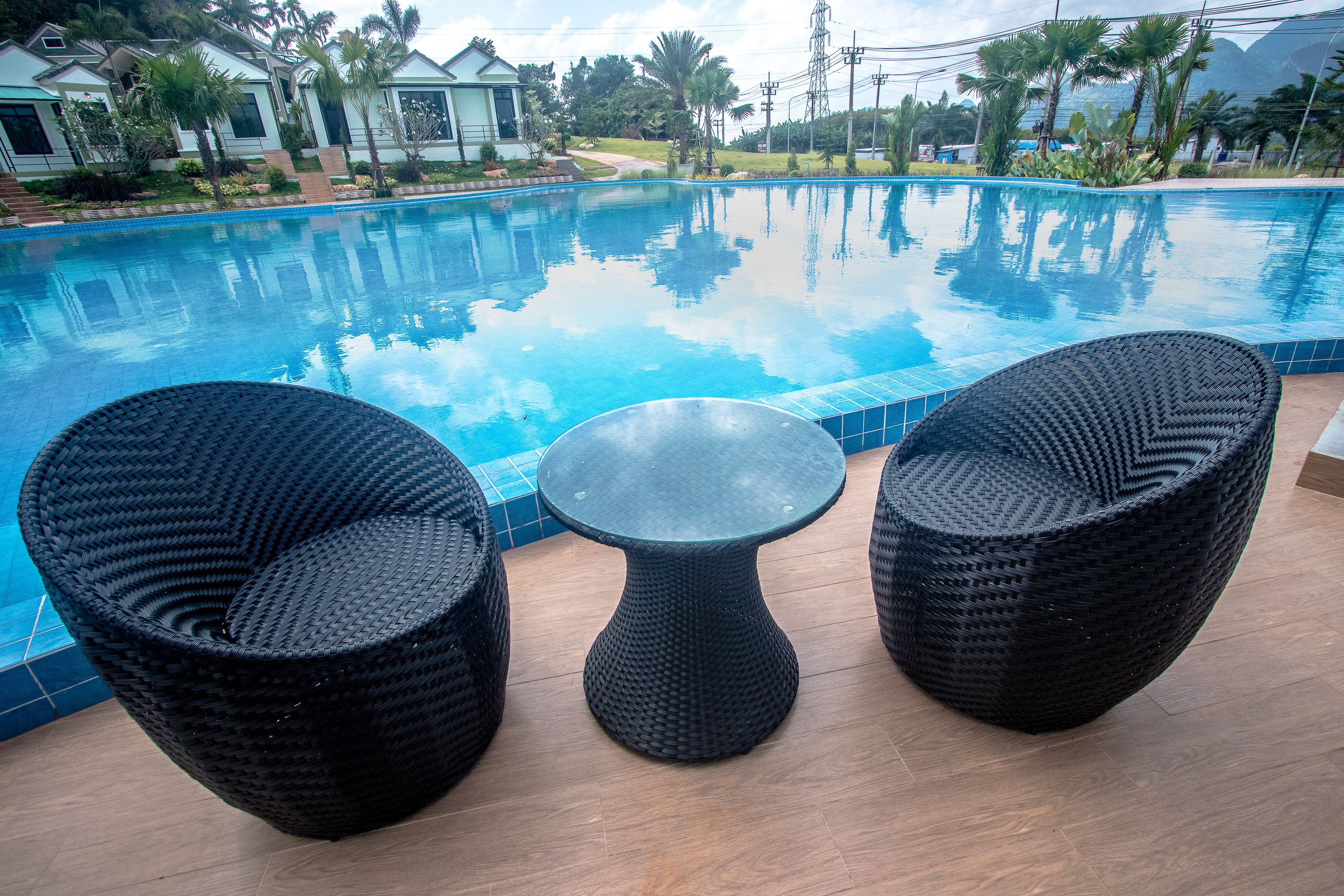 A poolside area with two wicker chairs and a small table.