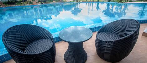 A poolside area with two wicker chairs and a small table.