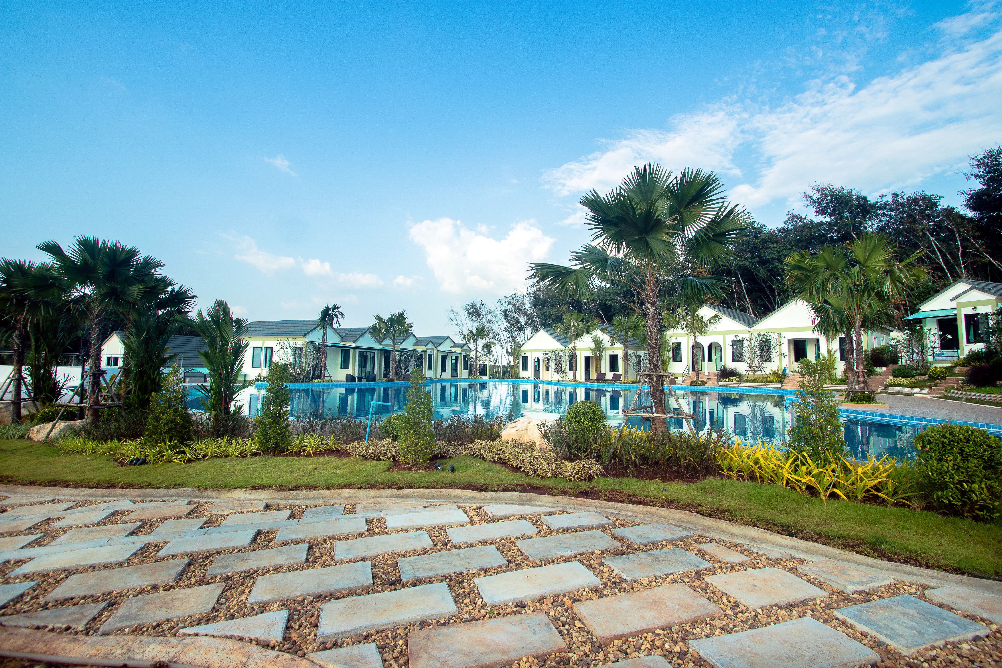 A resort with a swimming pool, palm trees, and a stone pathway.