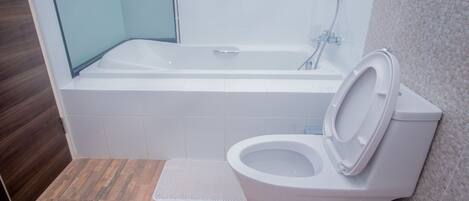 Un baño moderno con bañera, inodoro y zona de ducha.