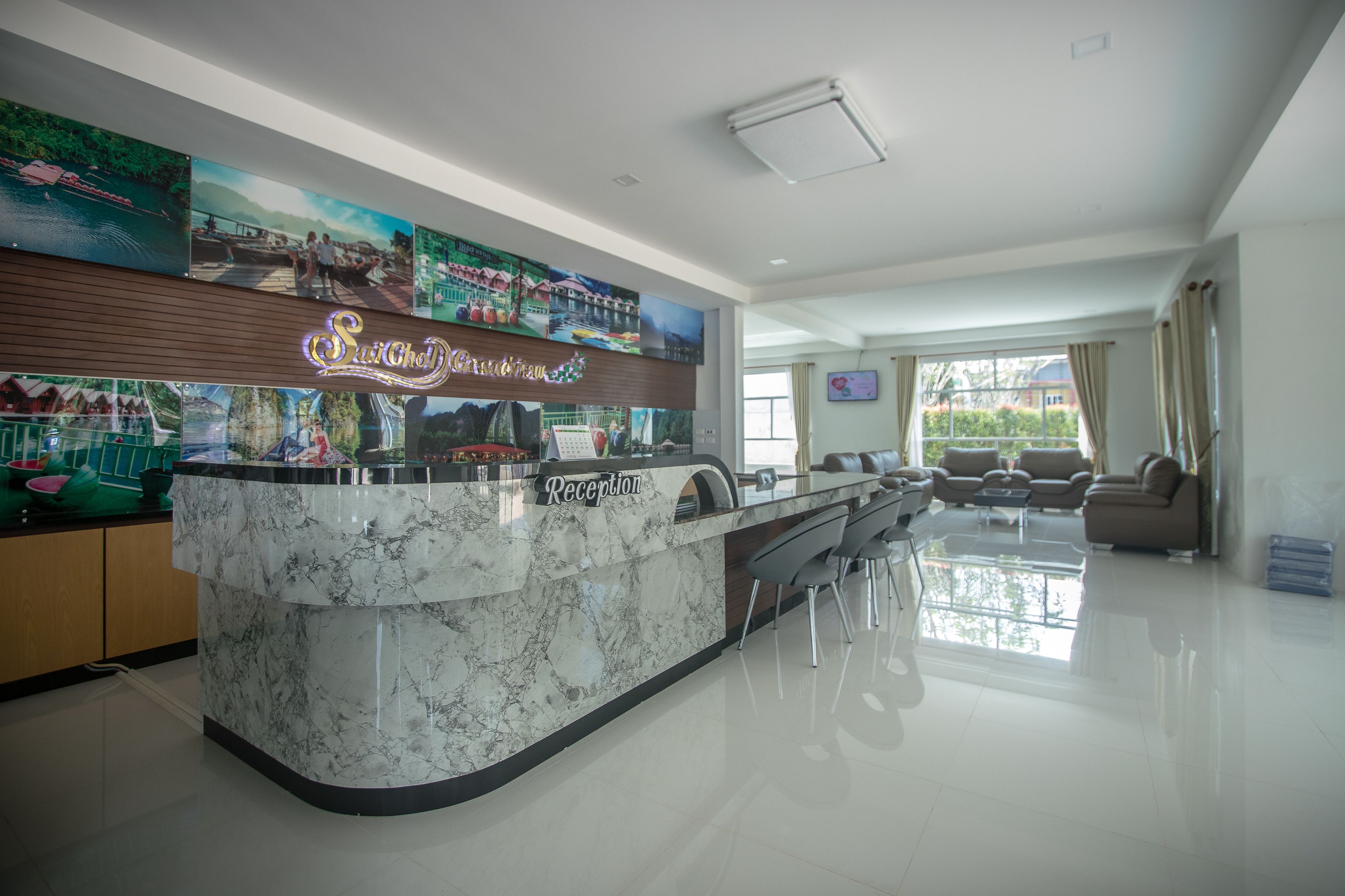 Een moderne hotel lobby met een receptiebalie, een zithoek en kunstwerken aan de muren.