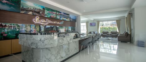 A modern hotel lobby with a reception desk, seating area, and artwork on the walls.