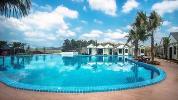 A swimming pool with a tiled edge, surrounded by palm trees and a clear sky.