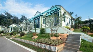 A modern house with a green roof, a staircase leading to the entrance, and a well-maintained garden with various plants and rocks. - Saichon Grand View Resort (Ban Ta Khun)