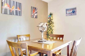 Un coin repas avec une table et des chaises en bois, une lampe décorative et des œuvres d’art murales.