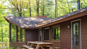A cabin with a deck, a picnic table, and large windows. - Pine Cottage on Blass Lake (Wisconsin Dells)
