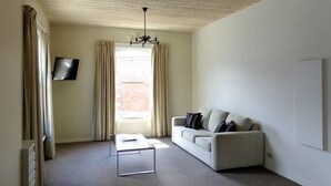 A minimalist living room with a sofa, a coffee table, and a TV mounted on the wall.