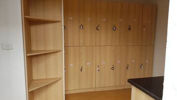 A room with wooden lockers, a black countertop, and a white wall with a light switch.