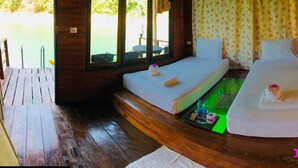Una habitación con dos camas, una mesita con botellas y vistas al exterior.