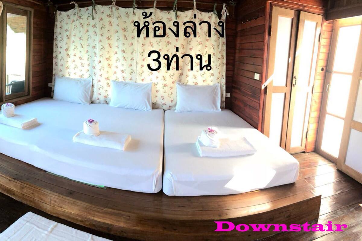 A wooden cabin bedroom with a large bed, two pillows, and a window with curtains.
