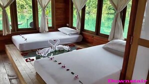 Una habitación con dos camas, cada una con sábanas y almohadas blancas, y suelo de madera.