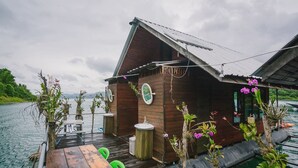 Una cabaña de madera con una pequeña terraza, un lavamanos y una mesa con sillas.