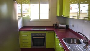 A kitchen with green cabinets, a red countertop, a stainless steel sink, and a window with blinds. - Stunning views to the sea / Fuengirola Apartment (Fuengirola)