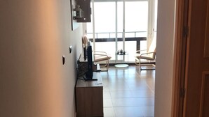 A hallway leading to a balcony with a view, a small seating area, and a door on the right. - Stunning views to the sea / Fuengirola Apartment (Fuengirola)
