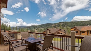 A wooden deck with outdoor furniture, a table, and chairs, overlooking a mountainous landscape with houses. - Luxury Home, Private Hot Tub, Enjoy Keystone, Breckenridge, A Basin, Copper! (Keystone)