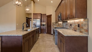 A kitchen with granite countertops, wooden cabinets, a stainless steel refrigerator, and a stone backsplash. - Luxury Home, Private Hot Tub, Enjoy Keystone, Breckenridge, A Basin, Copper! (Keystone)