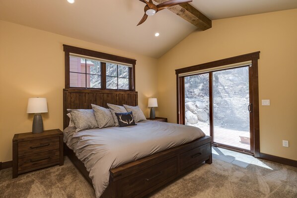 A bedroom with a large bed, two bedside tables, a ceiling fan, and a sliding glass door leading to an outdoor deck. - Luxury Home, Private Hot Tub, Enjoy Keystone, Breckenridge, A Basin, Copper! (Keystone)
