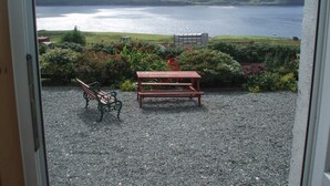 A view from a room with a gravel patio, a wooden bench, and a table. - SPACIOUS FAMILY FRIENDLY - AMAZING SEA VIEWS - SLEEPS 4-6 (Isle of Skye)