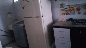 Une cuisine compacte équipée d’un réfrigérateur, d’un lave-linge et d’une cuisinière à gaz.